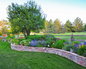 The gentle radius of this raised stone planter create an eye catching Colorado perennial bed